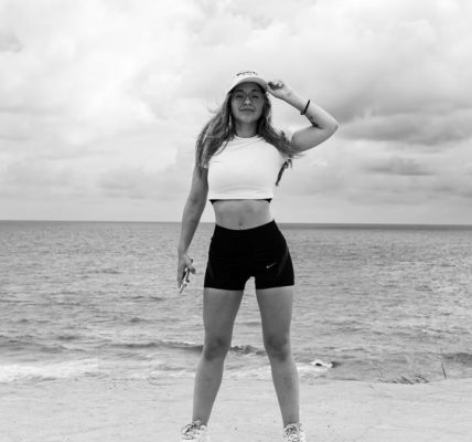 Black and white photo of a woman standing at the beach in Natal, Brazil, enjoying the ocean view.