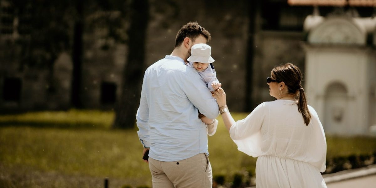 a man holding a baby while standing next to a woman