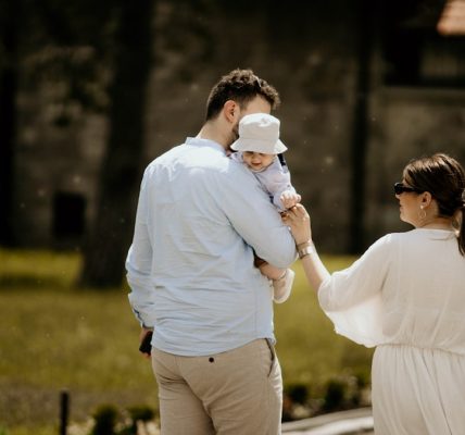 a man holding a baby while standing next to a woman