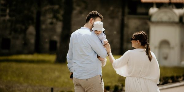 a man holding a baby while standing next to a woman